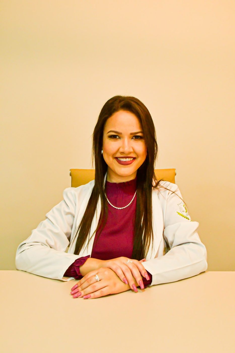 Retrato de Jheniffer Rodrigues sentada à mesa do consultório